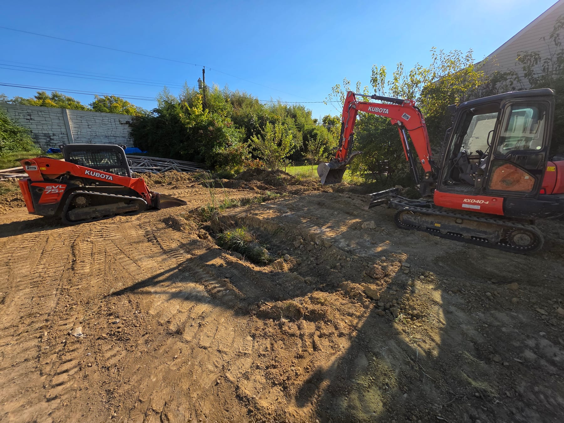 Excavator and compact track loader clearing the lot