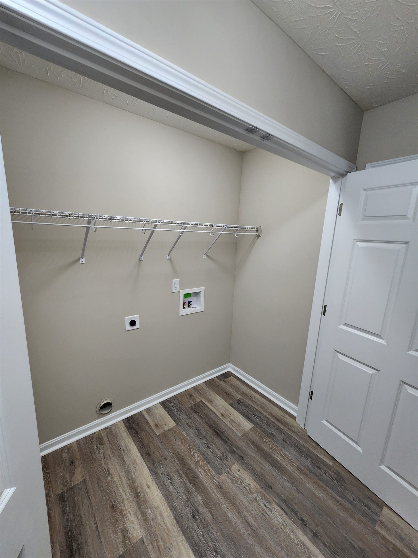Finished laundry closet with storage shelf and LVP flooring